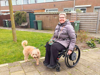 Vrouw in rolstoel met haar hond, ze draagt onze holster met daarin de flexi rollijn