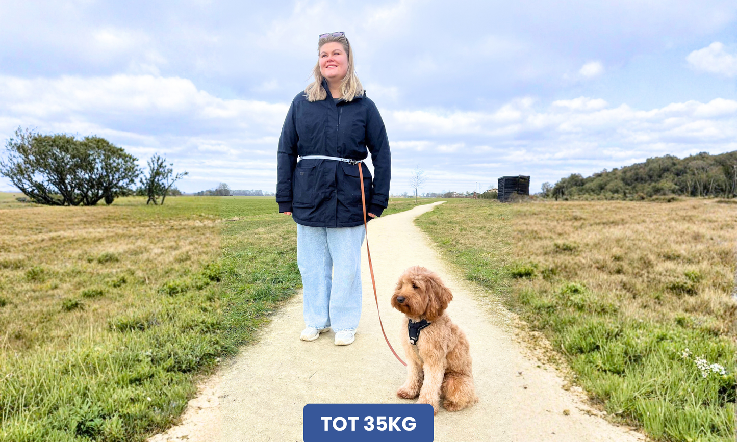 Vrouw met handsfree hondenriem die ze om haar heupen draagt en haar hond zit naast haar.