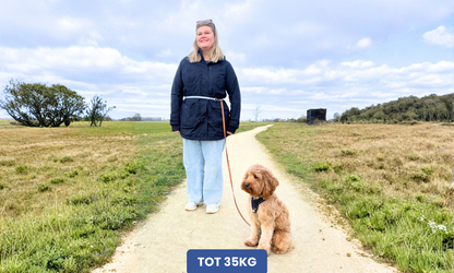 Vrouw met handsfree hondenriem die ze om haar heupen draagt en haar hond zit naast haar.